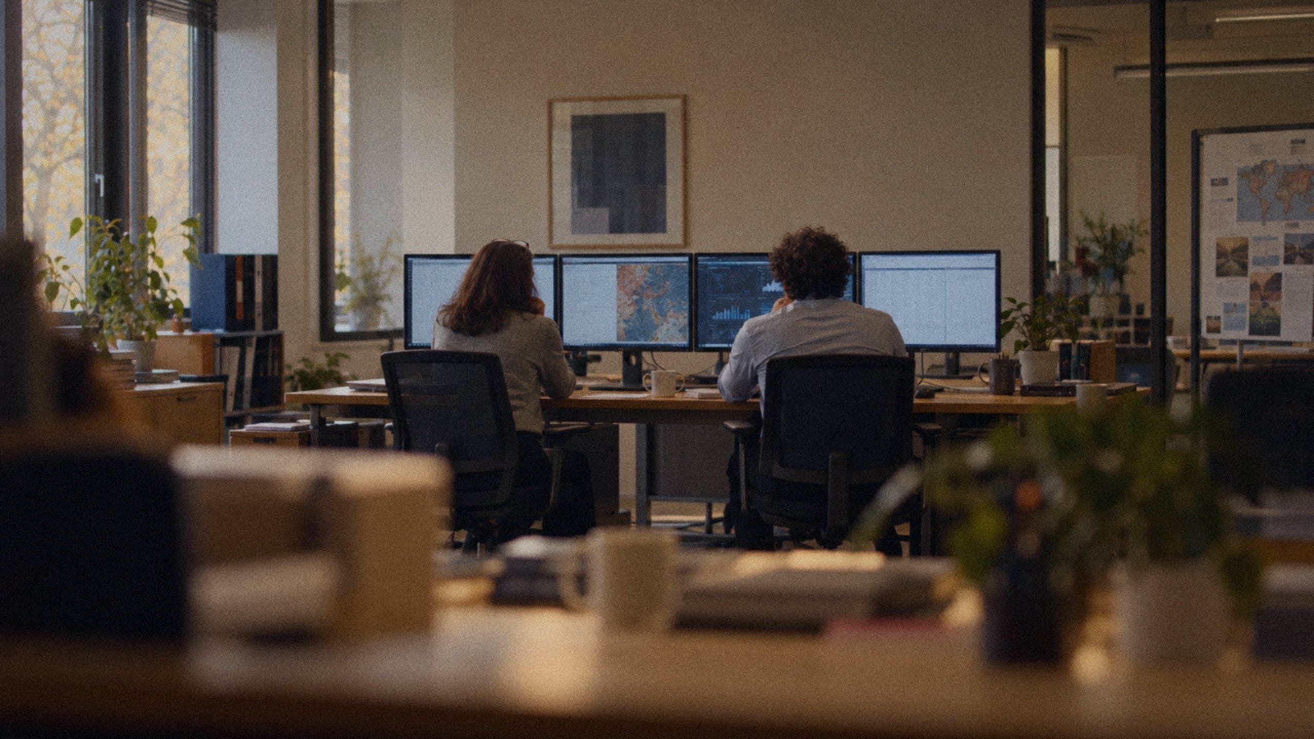 An engineer and an employee going through her work together at her desk.